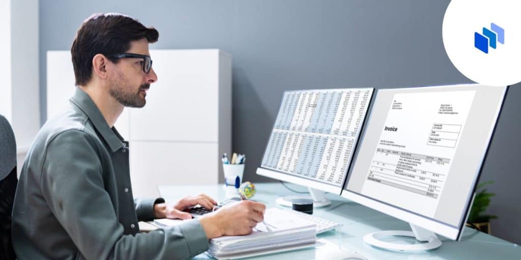 Man with facial hair sits at a desk with two screens.