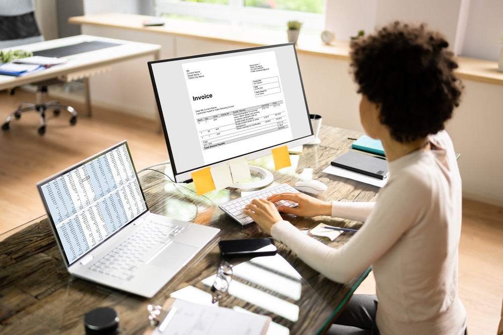 A woman working on a computer with an invoice on the screen